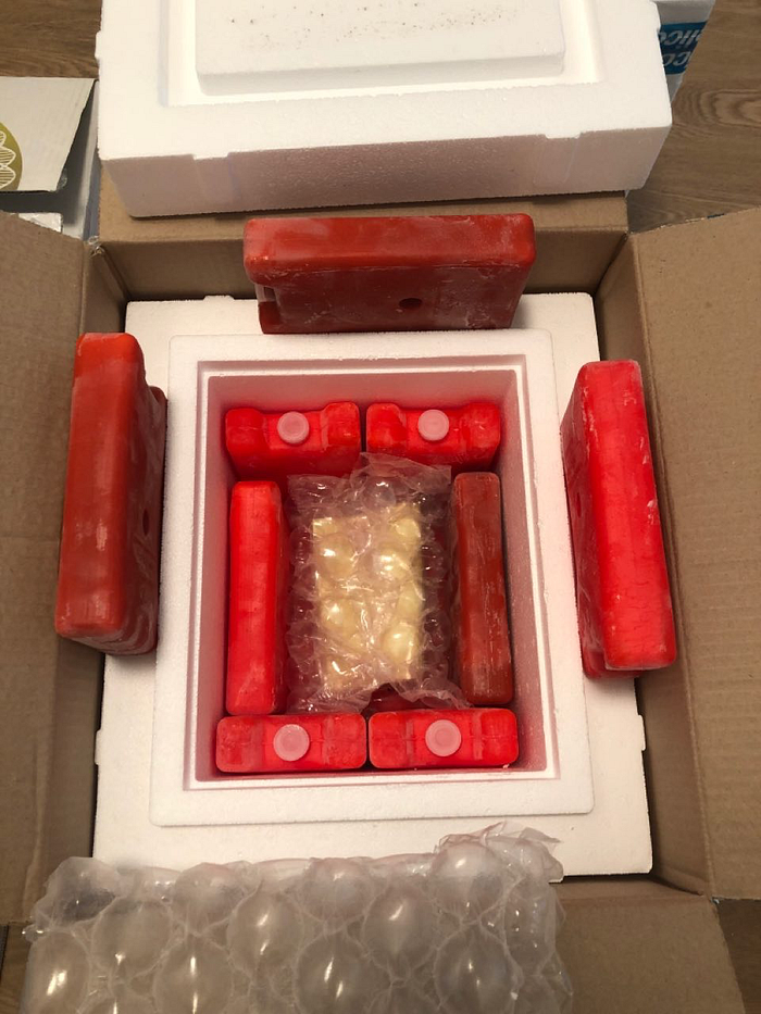 Insulated boxes with cold packs and the contents of the kit laid out on the table